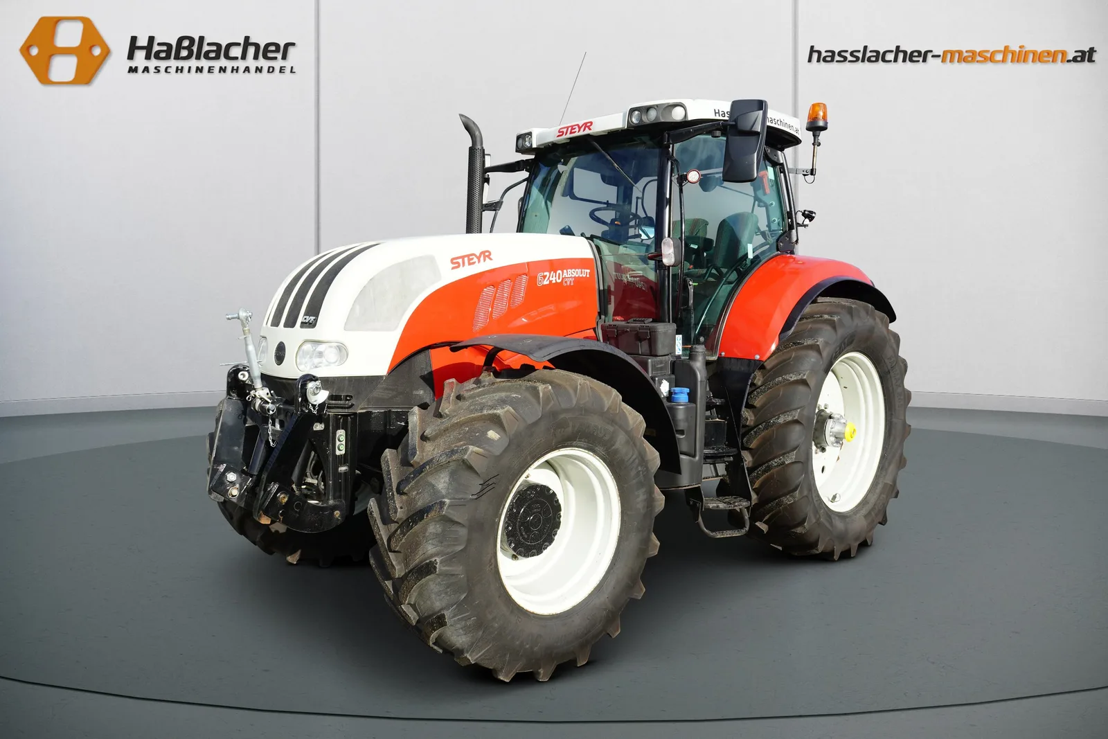 Steyr Traktor in Weiß und Rot von schräg vorne vor der Haßlacher-Fotowand