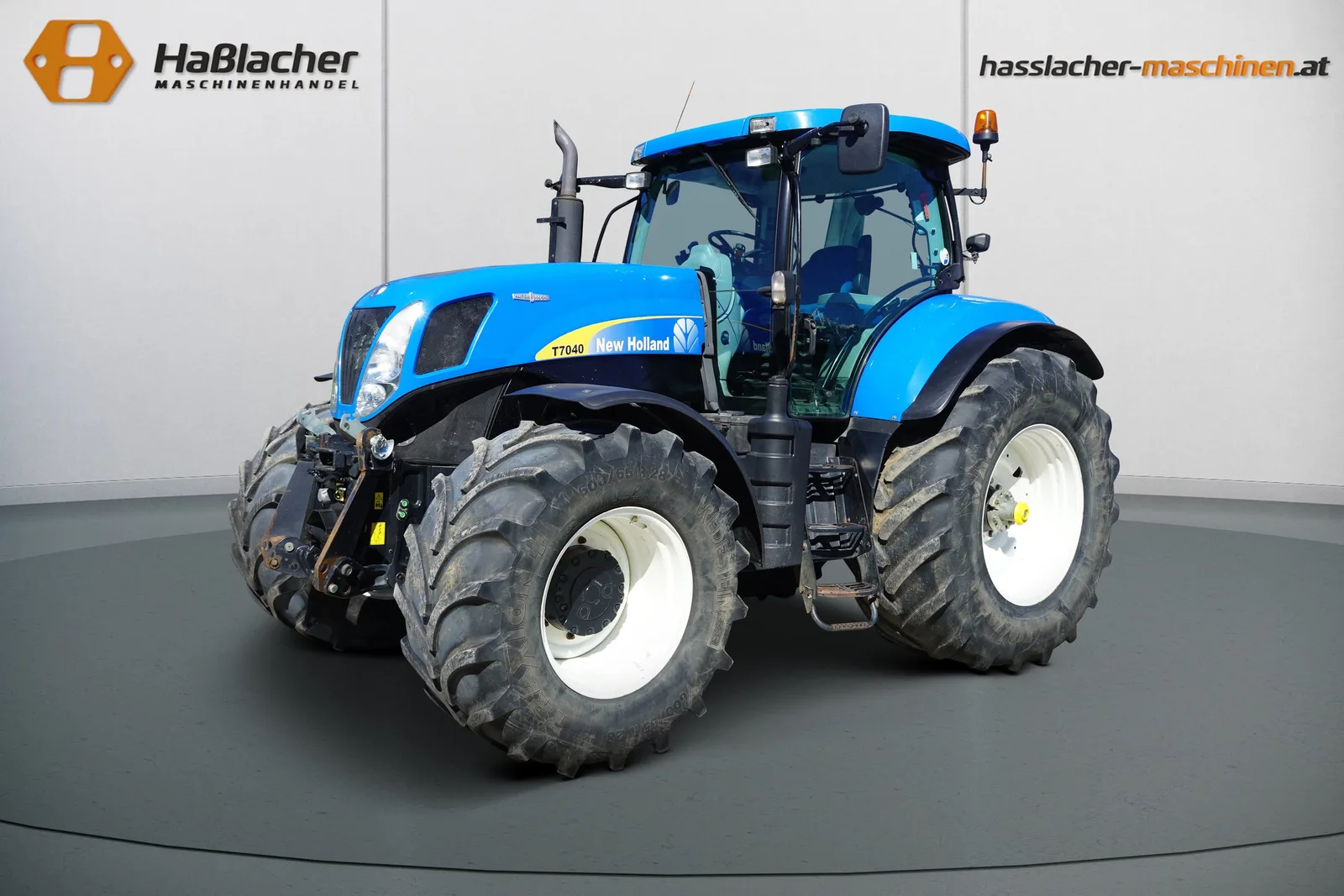 Hellblauer New Holland Traktor mit Frontgewicht vor der Haßlacher-Fotowand