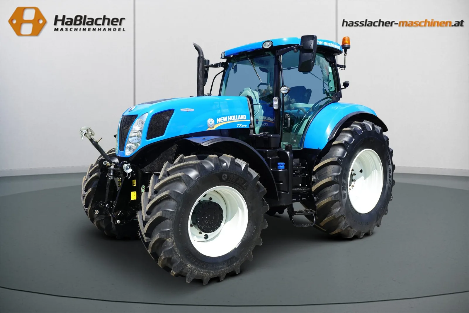 Hellblauer New Holland Traktor von schräg vorne vor der Haßlacher-Fotowand