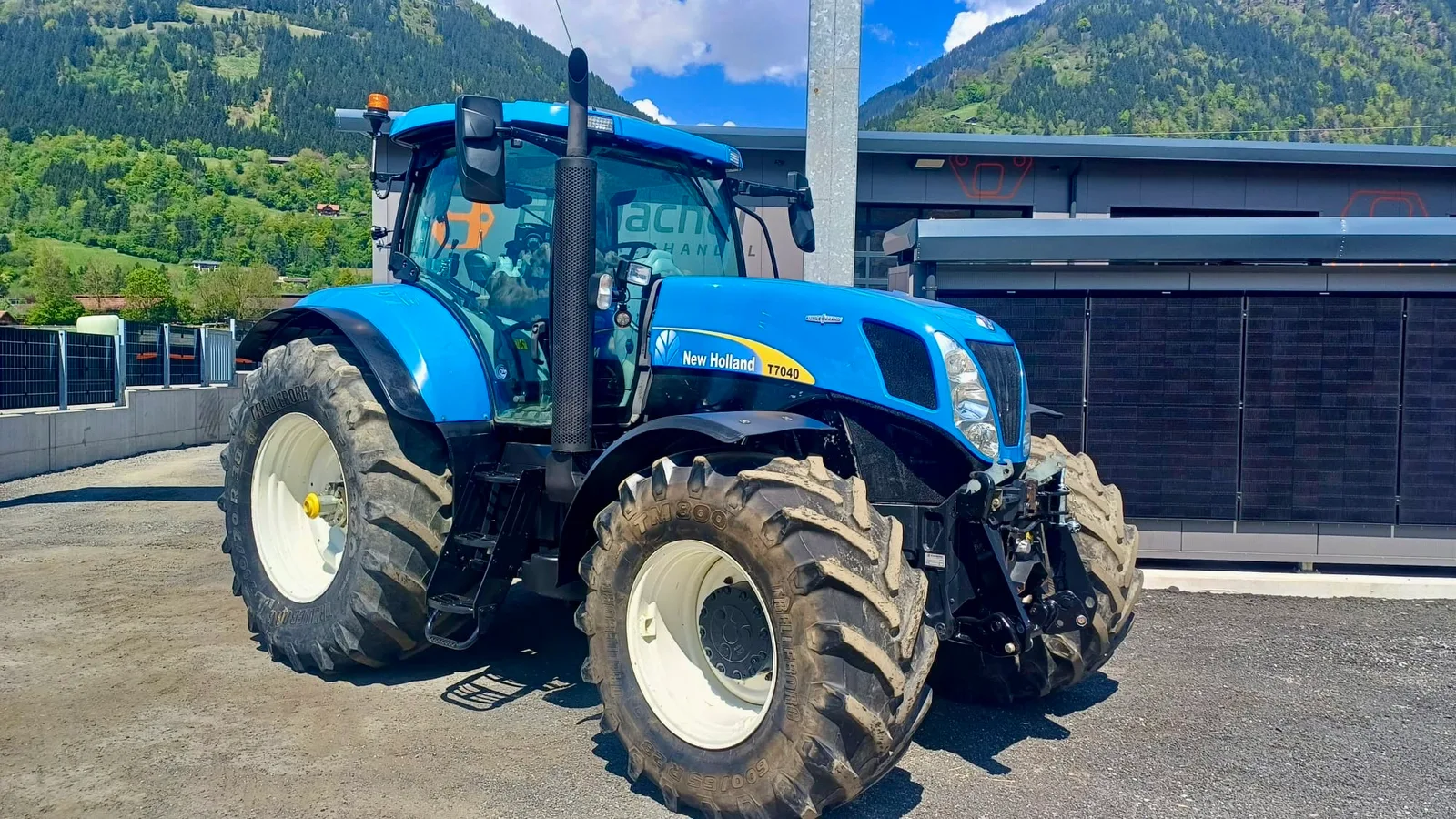 Blauer New Holland T7040 Traktor am Hof vor der Halle